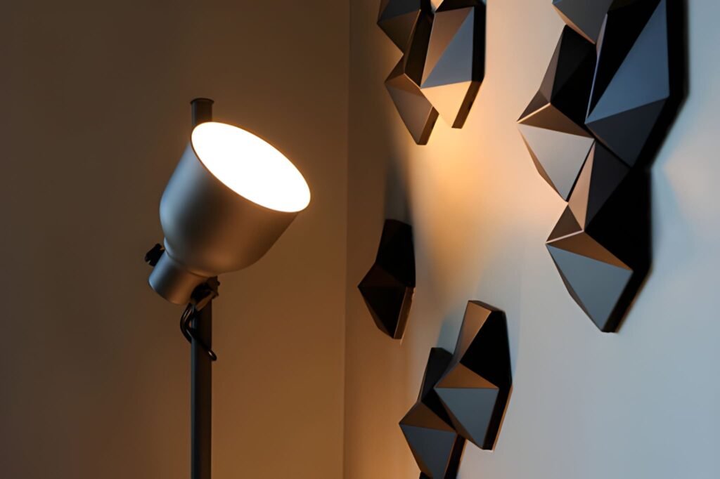 Lamp illuminating black geometric shapes on wall.