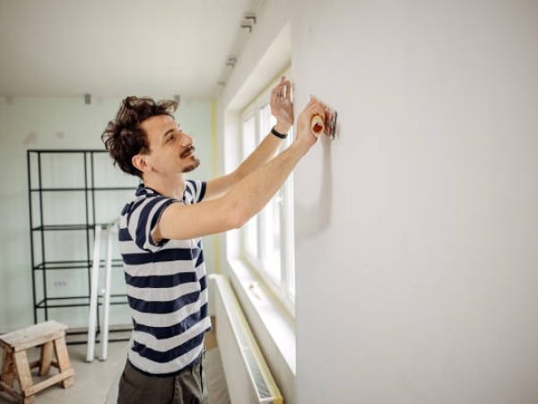 Man is preparing the wall for the painting.