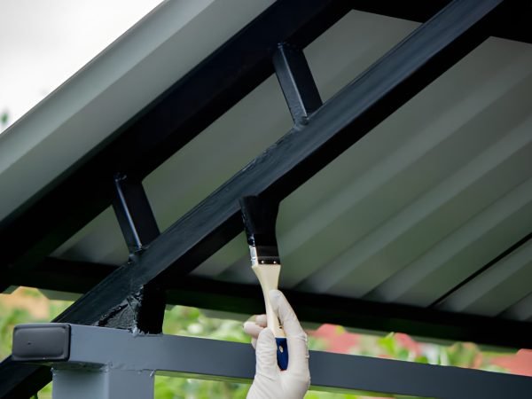 girl paint with a brush black metal. paints the roof. Selective focus