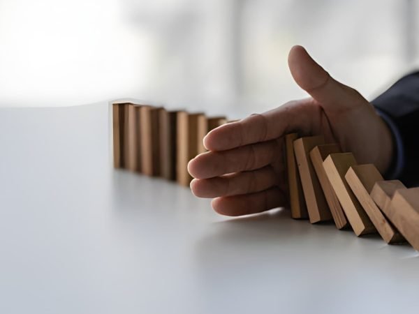 Hand stopping line of falling wooden dominoes.